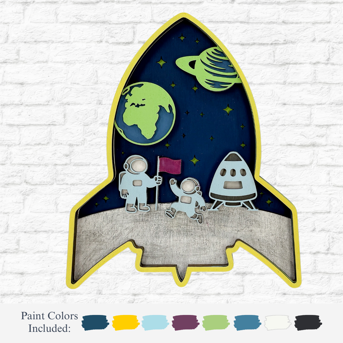 The Rustic Rhode’s DIY 3D Spaceship Kids Kit features a rocket-shaped shadow box with two astronauts, a spaceship, planets, and starry background—plus paint color samples for creative inspiration on your next space-themed project.