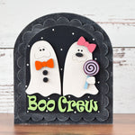 Decorate for Halloween with The Rustic Rhode DIY Boo Crew Arch Insert featuring two smiling ghosts with bows and buttons—one holding a lollipop—above green Boo Crew text on a black arch, perfect for your festive DIY projects.