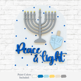 The Rustic Rhode’s DIY Hanukkah Peace & Light Arch Insert features a gray menorah with yellow flames, a blue-and-gray dreidel, and Peace & light in blue on a white background with blue polka dots. Paint colors shown below.
