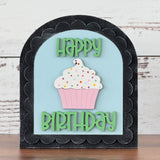 Decorative birthday sign with a cupcake and 'Happy Birthday' text on a light blue background.