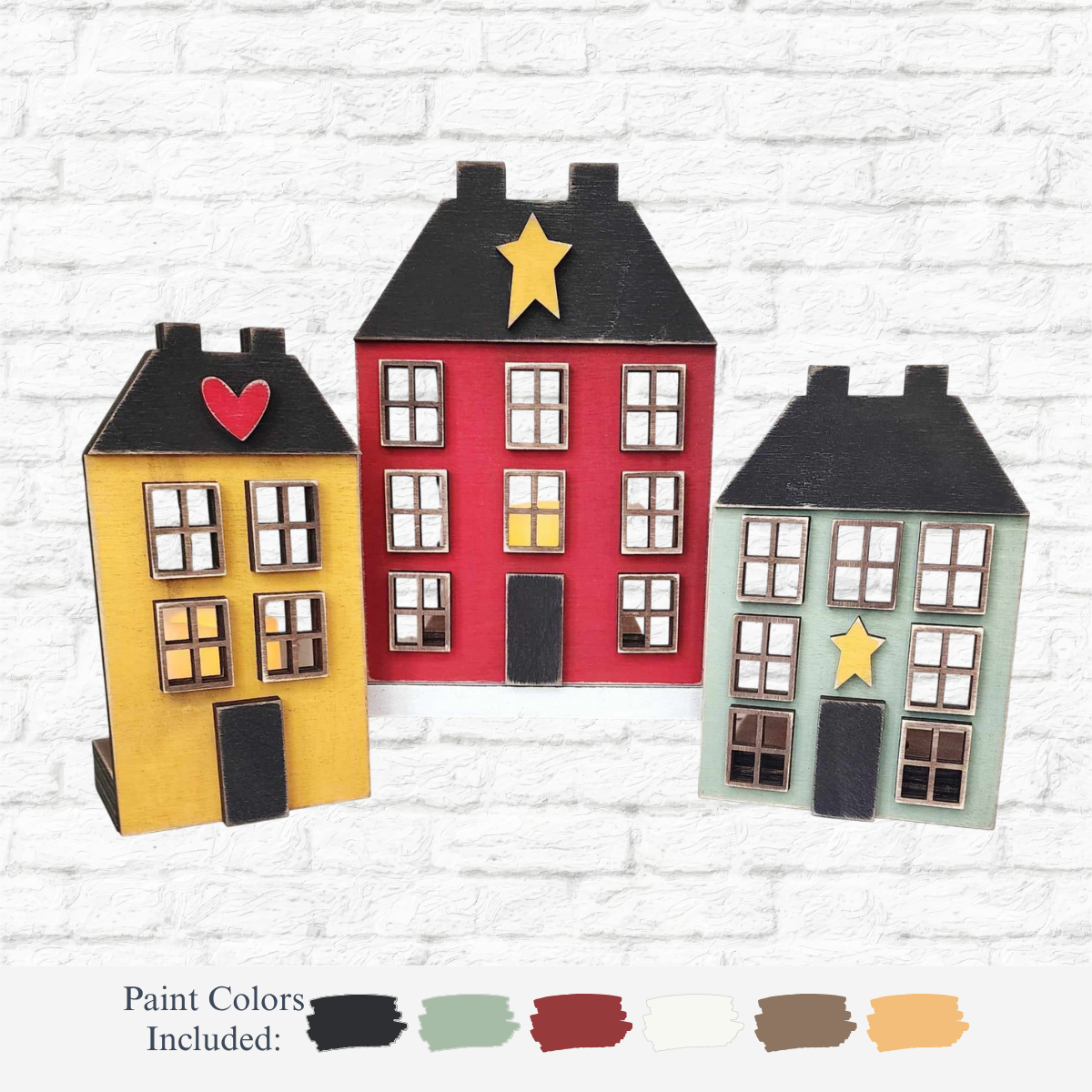 The Rustic Rhode’s DIY Primitive Salt Box Houses—Set of 3—features wooden mini houses in different colors with star and heart cutouts, plus a color palette of six paint swatches, displayed against a white brick wall.