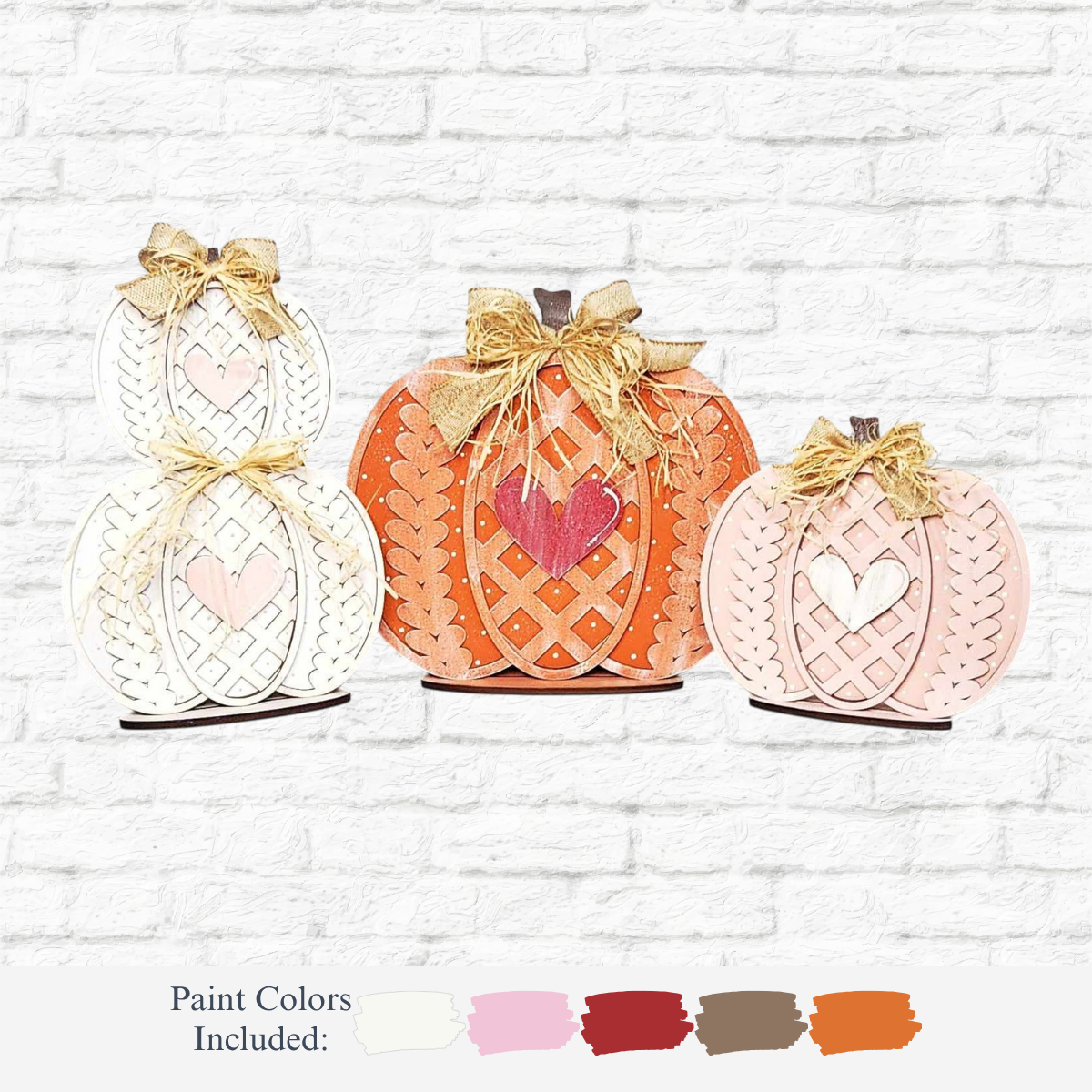 The Rustic Rhodes DIY Standing Fall Pumpkins- Set of 3 feature cut-out hearts and bows in white, orange, and pink, making charming fall décor against a white brick wall. Five paint color samples are displayed below.