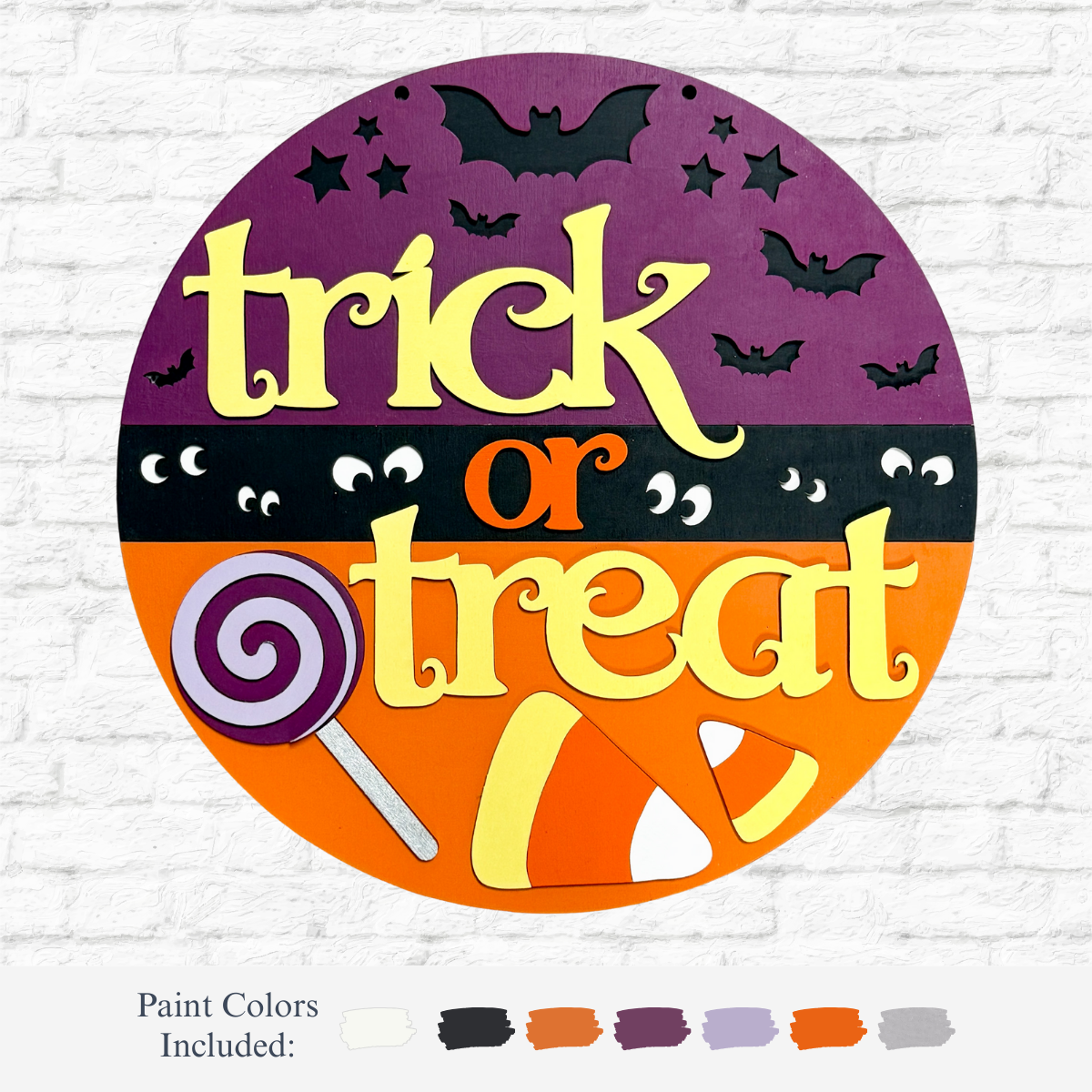 The Rustic Rhode DIY Trick or Treat Door Hanger is a round Halloween sign featuring “trick or treat” in yellow and orange, plus bats, stars, eyes, a lollipop, and candy corn—the perfect craft kit to add festive flair to your décor!.
