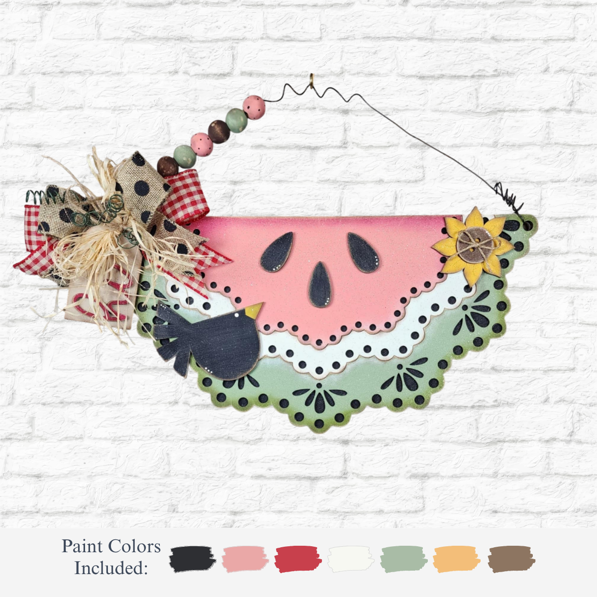 The Rustic Rhodes DIY Watermelon Slice Sign features laser-cut wood, a scalloped edge, polka dot bow, checkered ribbon, raffia, sunflower, and bird accents. Includes six paint color swatches on a white brick background—ideal for summer decor.