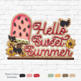 The Rustic Rhodes DIY Watermelon Word Block features a wooden sign with a pink watermelon slice, sunflowers, and two black birds. It reads Hello Sweet Summer in red. Ideal as seasonal home decor or a summer craft kit with paint color options available.
