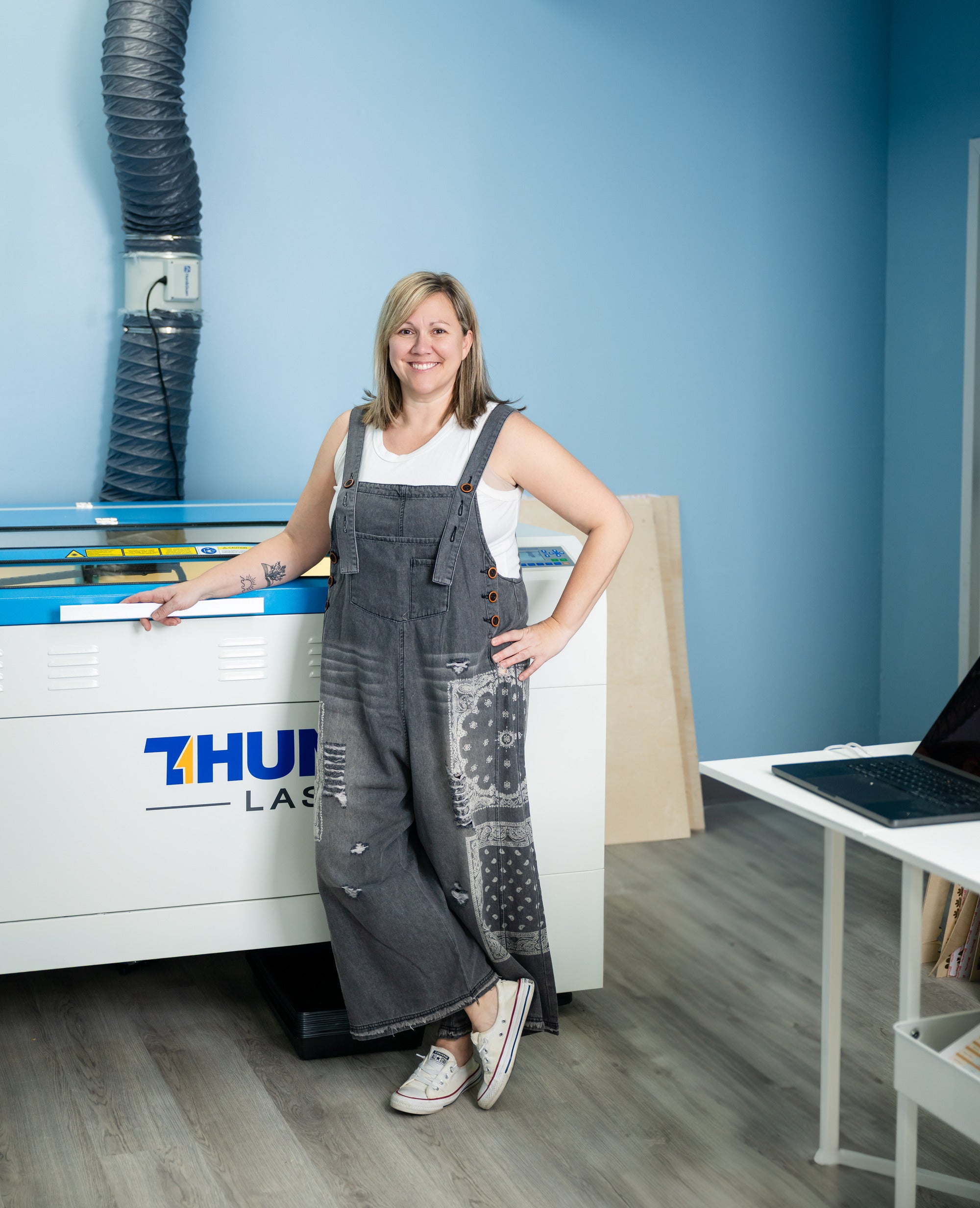 Rustic Rhode founder standing next to lazer cutter at her Rhode Island craft studio