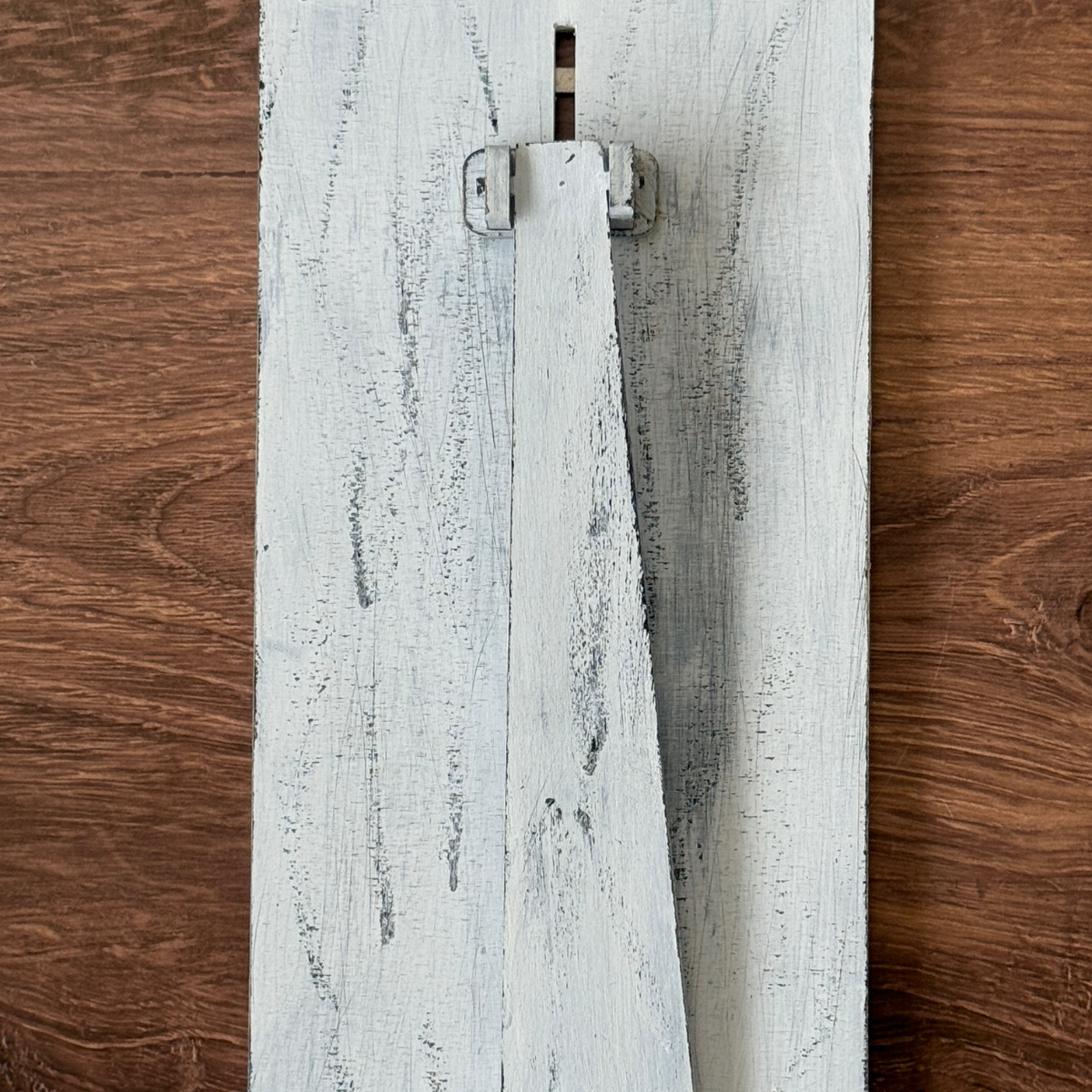 The Rustic Rhode DIY Firefly Interchangeable 4.25 Insert features a distressed white wooden board with a vertical rectangular rotating latch, perfect for farmhouse frames or creative projects, set against a brown wood background.