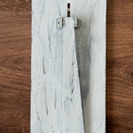The Rustic Rhode DIY Firefly Interchangeable 4.25 Insert features a distressed white wooden board with a vertical rectangular rotating latch, perfect for farmhouse frames or creative projects, set against a brown wood background.
