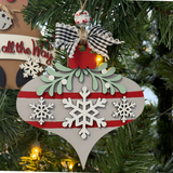 The Rustic Rhode's DIY Mistletoe Ornament—Snowflakes features a gray and red design with white snowflakes, green leaves, and a checkered bow, perfect for painting at home or gifting as an unassembled ornament kit. Warm lights add festive cheer.