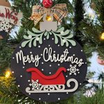 The Rustic Rhode DIY Mistletoe Ornament- Santa's Sleigh features “Merry Christmas” in white, a red sleigh, snowflakes, greenery, and a plaid bow—ready to hang or decorate with paint bead accents for a festive tree.