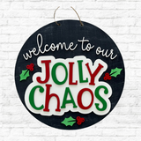 A round black sign with festive accents hangs on a white brick wall—a charming piece from The Rustic Rhode for Cathy's Craft Night, November 13th at 6:00pm, perfect for your holiday decor or as a seasonal door hanger.