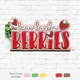 The Rustic Rhode’s DIY Berry Sweet Word Block craft kit features farm fresh BERRIES with strawberry and daisy accents, displayed on a white brick wall. Includes pink, green, yellow, red, and white paint colors.