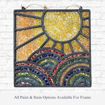 The Rustic Rhodes DIY Chasing Rainbows Faux Suncatcher is a square stained glass art piece with a yellow sun, vibrant arched hills in red, blue, green, and yellow tones, beautifully displayed against a white brick wall.