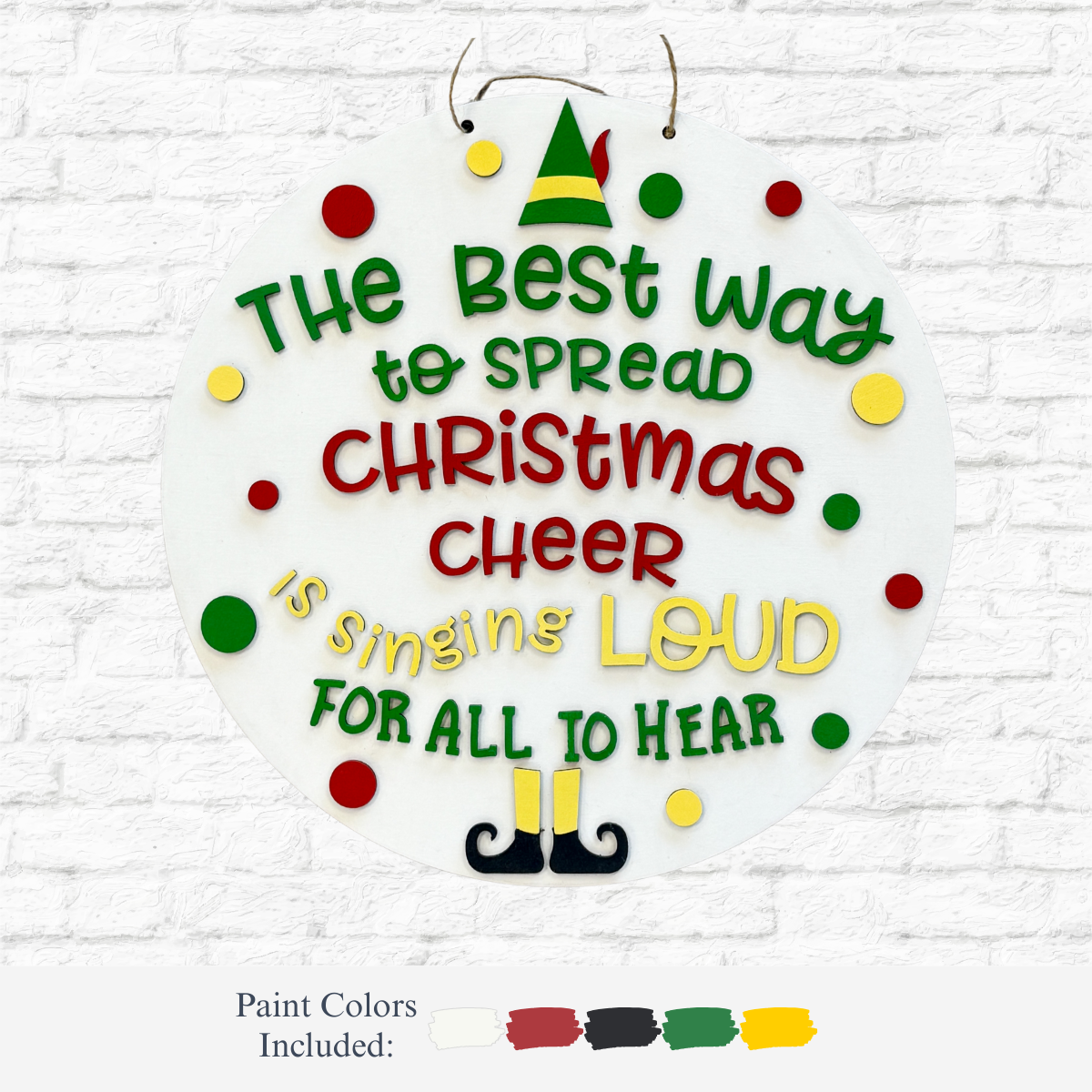 The Rustic Rhode DIY Christmas Cheer Door Hanger features a round design with colorful text, dots, an elf hat and shoes, plus festive paint colors. It reads: The best way to spread Christmas cheer is singing loud for all to hear.