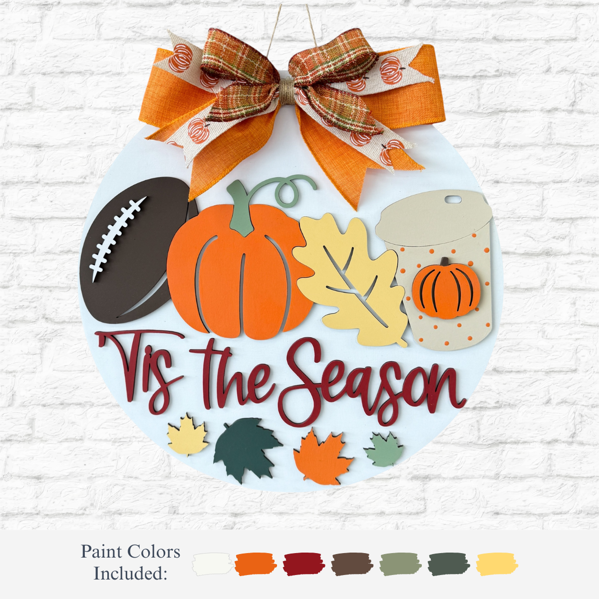 The Rustic Rhode DIY Fall Tis The Season Door Hanger features a round design with plaid and orange bow, football, pumpkin, leaf, jar cutouts, and Tis the Season text—perfect for autumn décor or as a fall craft kit.