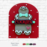 The Rustic Rhode’s DIY Gingerbread Cookie Arch Insert features a smiling gingerbread with a green bow tie and COOKIES sign. Includes festive paint colors—green, brown, red, black, and white—great for your holiday craft kit!.