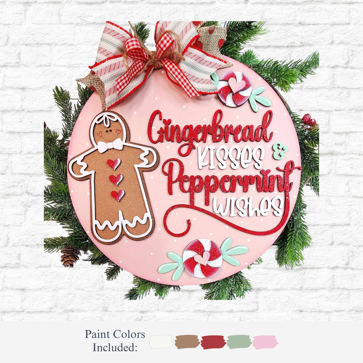 The Rustic Rhode DIY Gingerbread Door Hanger features a round pink holiday sign with a gingerbread, peppermint candies, “Gingerbread Kisses & Peppermint Wishes” text, topped with a red plaid bow and greenery. Paint colors shown below.