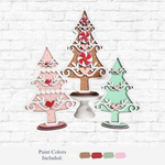 The Rustic Rhode DIY Gingerbread Trees kit includes three festive tree cutouts in pink, brown, and green with heart and candy designs. Paint colors are shown below the trees. Perfect as a charming rustic holiday decor door hanger!.
