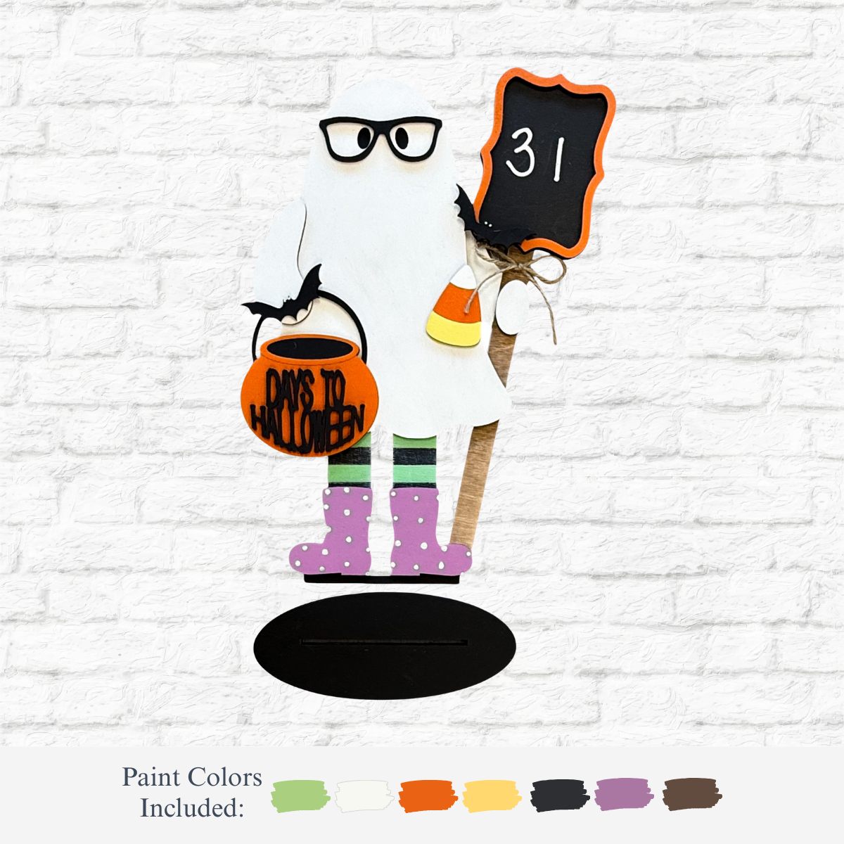 The Rustic Rhode’s DIY Halloween Countdown Ghost features glasses, holds a “31” chalkboard, a pumpkin bucket labeled “Days to Halloween,” and a candy bucket. It stands on a black oval base perfect for your festive décor.