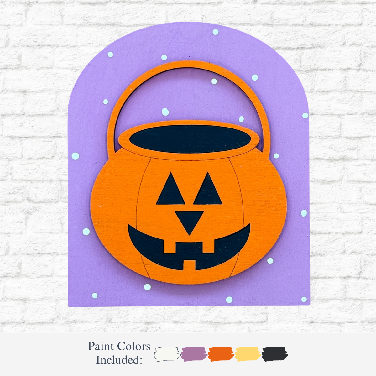 The Rustic Rhode DIY Halloween Jack-O-Lantern Arch Insert features an orange pumpkin bucket with a jack-o’-lantern face on a purple, arched background—ideal for Halloween crafts. Paint colors: white, black, orange, yellow, and purple.