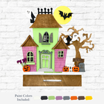The Rustic Rhode’s DIY Haunted House Kit features a colorful Halloween scene with ghosts, bats, pumpkins, and a spooky tree on a white brick wall. Below are paint color samples and the label “Paint Colors Included.”.