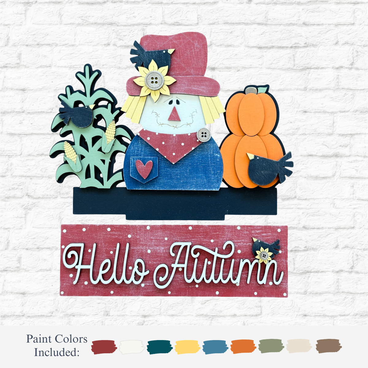 The Rustic Rhode’s DIY Hello Autumn 2 Piece Insert features a scarecrow, sunflowers, corn, pumpkin, blackbird, and a red Hello Autumn sign with paint color samples—perfect for creating or displaying your own fall decor.