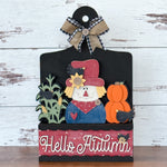 The Rustic Rhode DIY Hello Autumn 2 Piece Insert features a scarecrow, pumpkins, corn stalks, blackbirds, and a plaid bow—a charming handmade fall decor or interchangeable window frame insert.