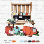 A rustic display features The Rustic Rhode’s DIY Hello Pumpkin Shelf Sitter with wooden pumpkins, a black pickup, a small house, and autumn decor on a bench—perfect for showcasing handmade shelf pieces. Paint color swatches appear below.