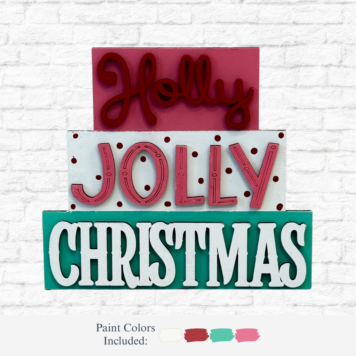 The Rustic Rhode's DIY Holly Jolly Christmas Word Stacker features wooden signs reading "Holly Jolly Christmas" in red, pink, and green polka dots on a white brick background. Kit includes white, red, green, and pink paint.