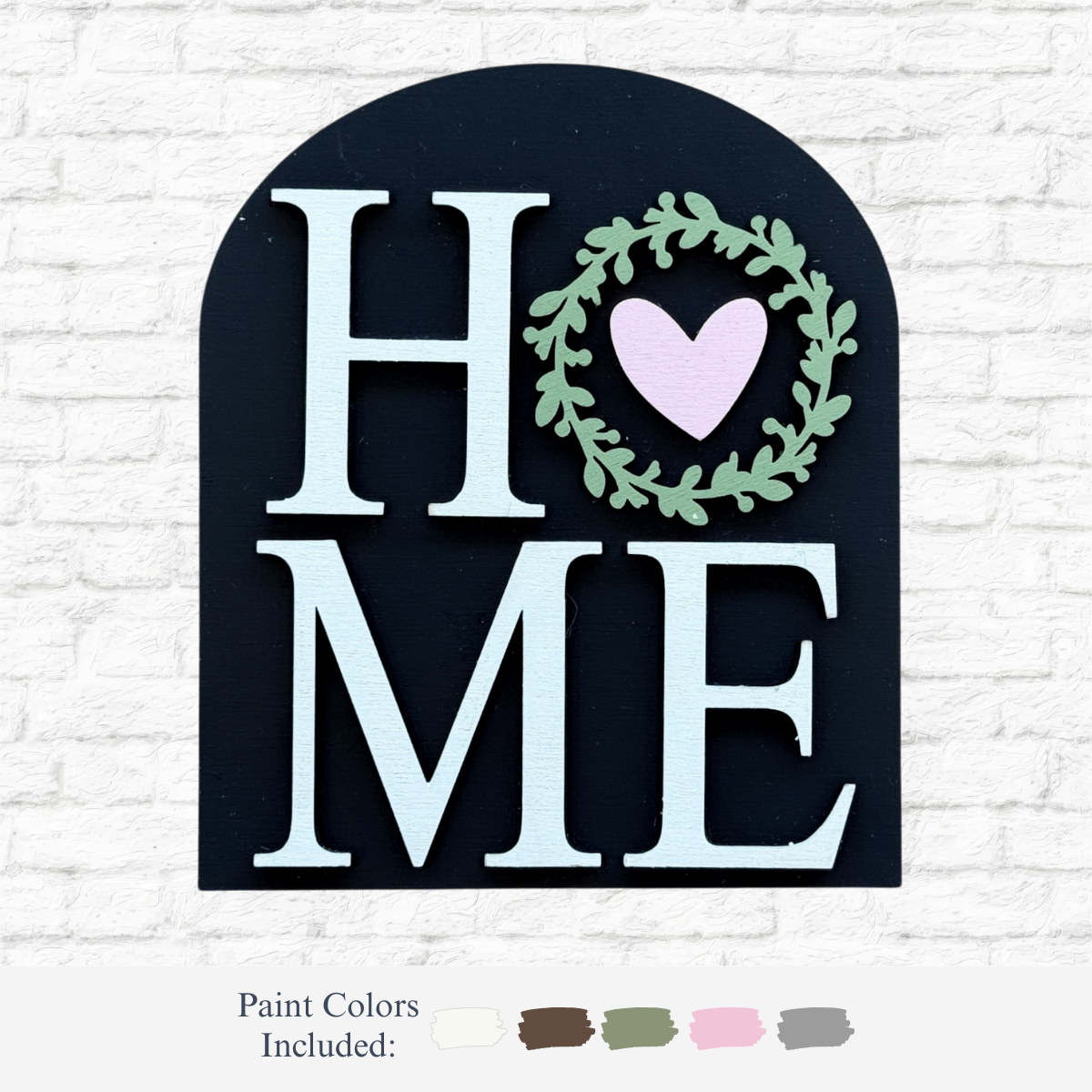 The Rustic Rhode’s DIY Home Arch Insert features “HOME” with a wreath and heart as the O on a black arch. Includes white, beige, brown, green, and pink paints—perfect for adding a cozy touch to your décor.