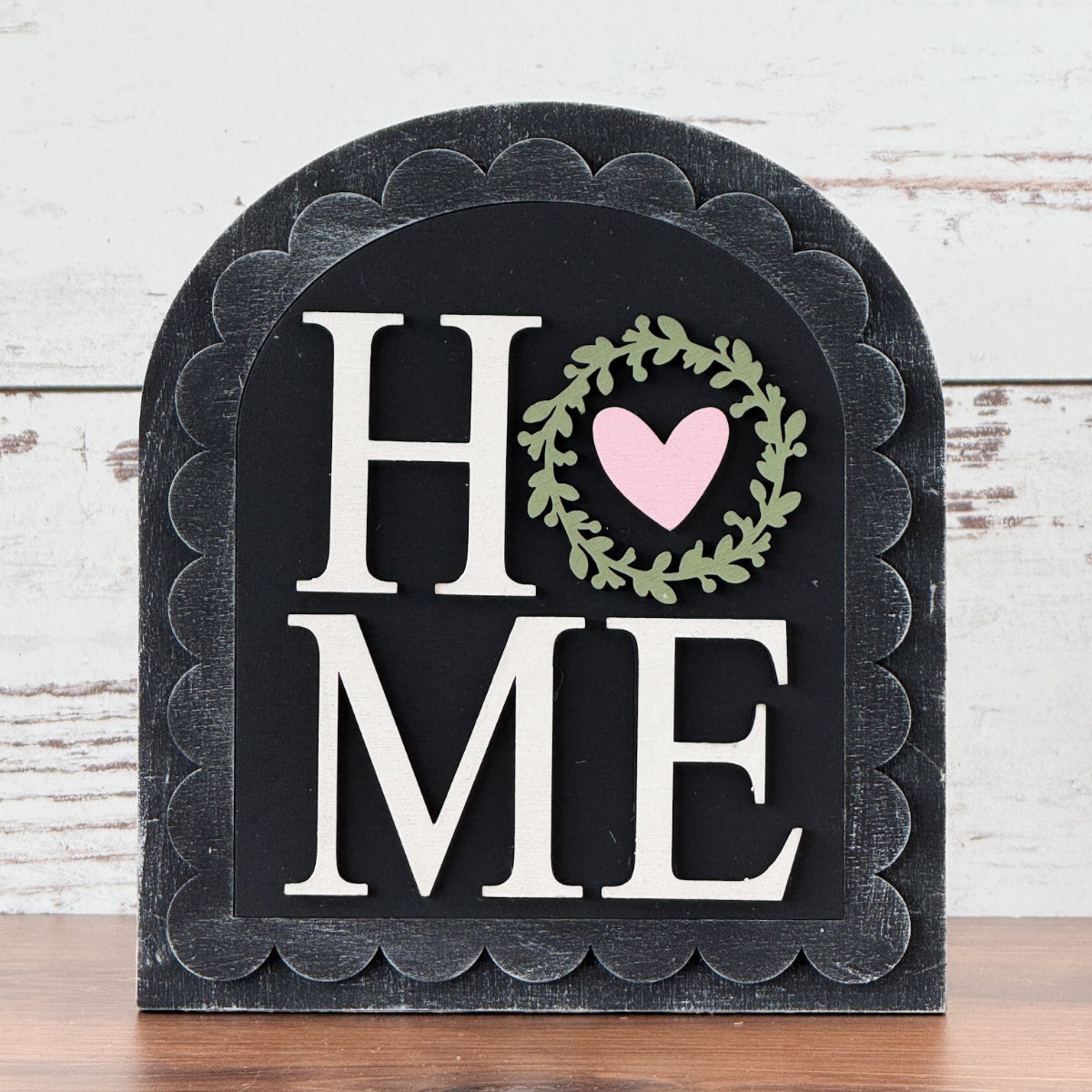 Decorative sign with 'HOME' and heart design on a wooden surface and white wooden background