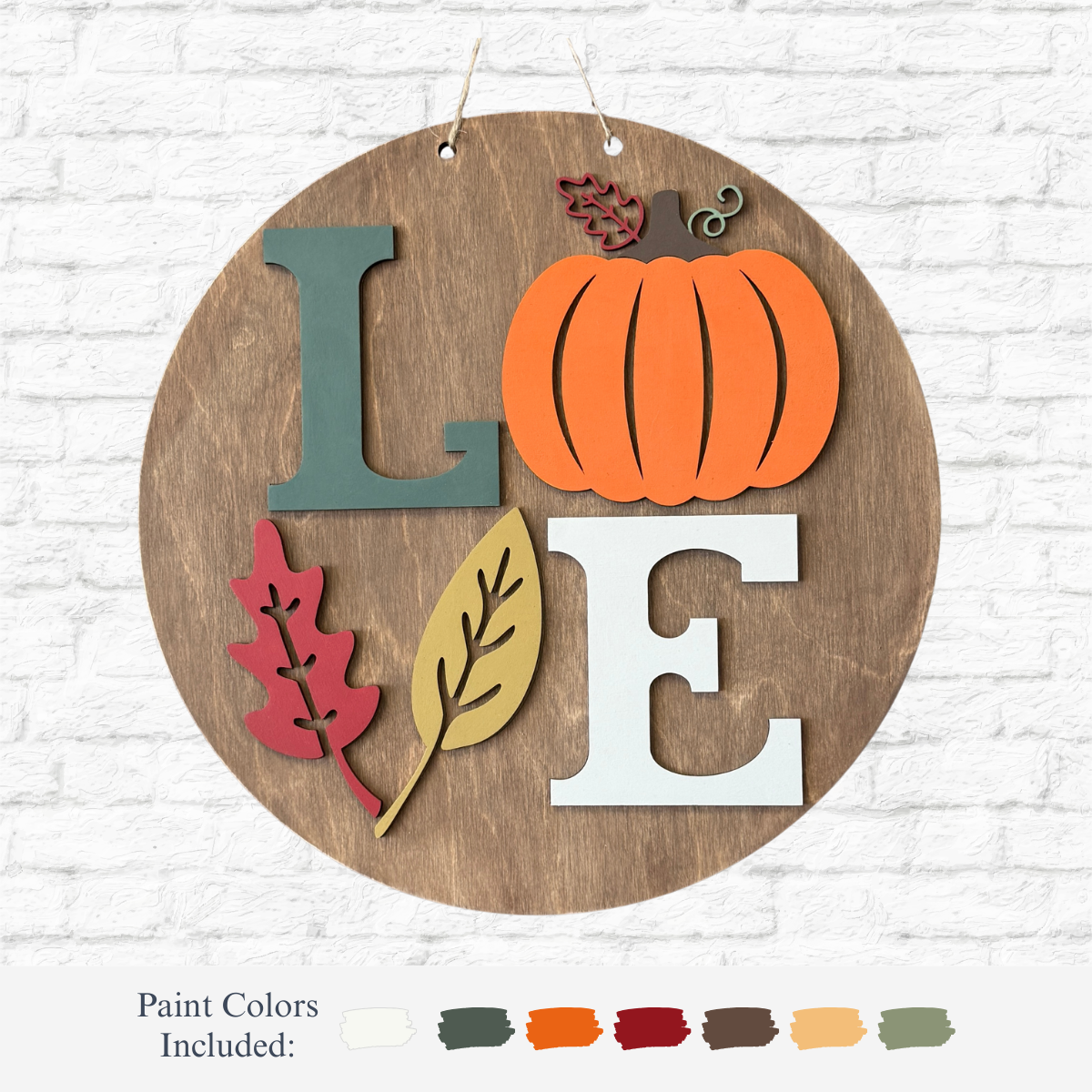 The Rustic Rhode DIY Love Fall Pumpkin Door Hanger features a round wooden sign with LOVE in fall colors, a pumpkin for the O, leaf accents, and paint color samples on a white brick background.