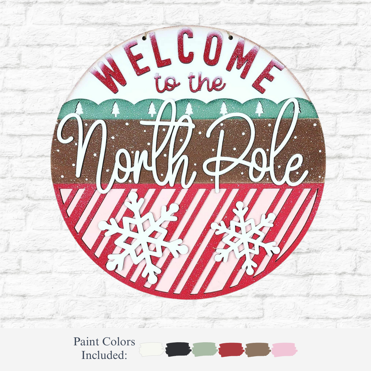 The Rustic Rhode DIY North Pole Door Hanger features "Welcome to the North Pole" with snow, trees, and snowflakes. This festive round sign has a green, brown, and red striped background; paint colors are shown below for your DIY project.