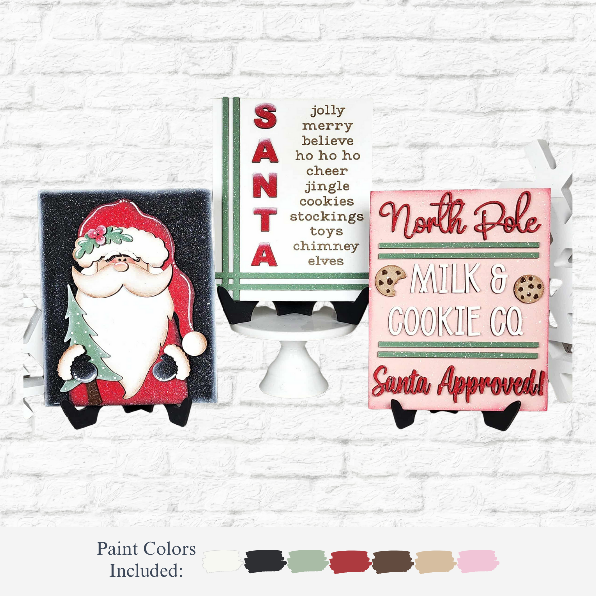 The Rustic Rhode DIY North Pole Sign Trio includes three festive mini wooden signs: one with a Santa illustration, one with a SANTA acrostic, and one reading "North Pole Milk & Cookie Co. Santa Approved!" Paint swatches shown below.