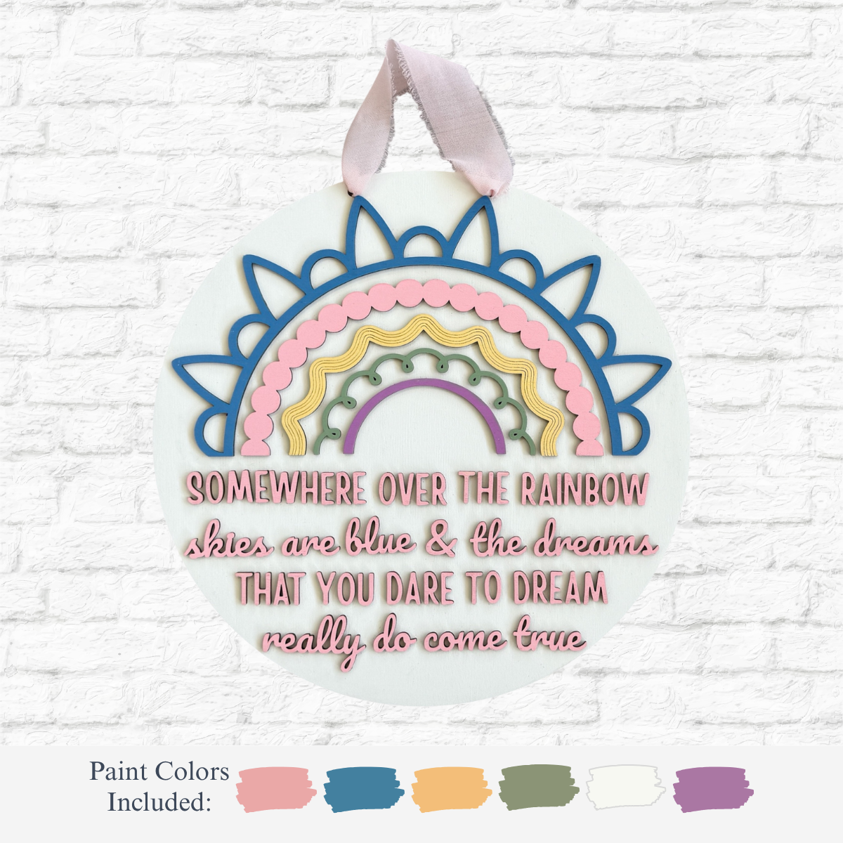 The Rustic Rhode DIY Under The Rainbow Sign features a pastel rainbow and the quote “Somewhere over the rainbow skies are blue & the dreams that you dare to dream really do come true”—a whimsical Wizard of Oz-inspired nursery decor piece.