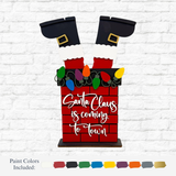 The Rustic Rhode’s DIY Santa Chimney kit features Santa’s legs in a red brick chimney with colorful lights and “Santa Claus is coming to town” on the front. Paint colors are displayed below.
