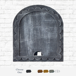 The Rustic Rhode’s DIY Scalloped Arch Insert Frame in black stands against a white brick wall, with six neutral paint swatches below and the text Choose One: displayed.