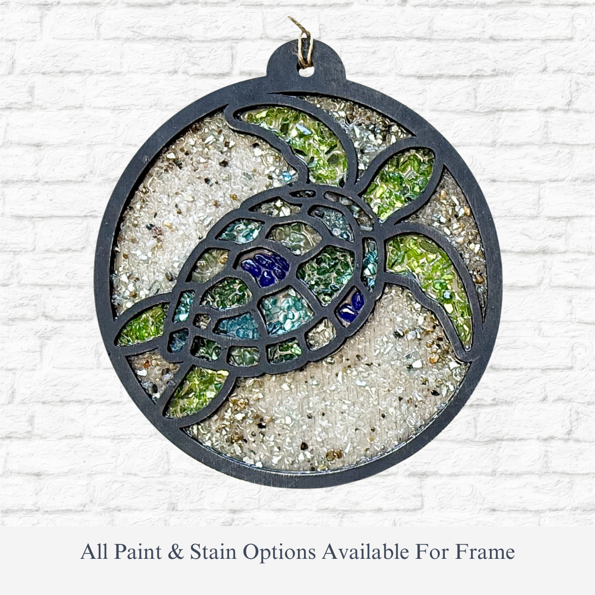 The Rustic Rhode DIY Sea Turtle Faux Suncatcher features a round stained glass ornament with green, blue, and clear pieces, sandy textured background, laser-cut wood frame, and a small top hook for hanging.
