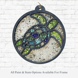 The Rustic Rhode DIY Sea Turtle Faux Suncatcher features a round stained glass ornament with green, blue, and clear pieces, sandy textured background, laser-cut wood frame, and a small top hook for hanging.