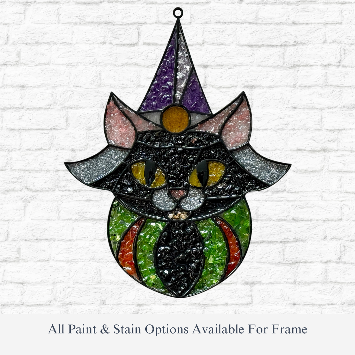 The Rustic Rhodes DIY Spells & Whiskers Faux Suncatcher hangs on a white brick wall, its stained glass-style cat and laser-cut wooden frame adding charm.