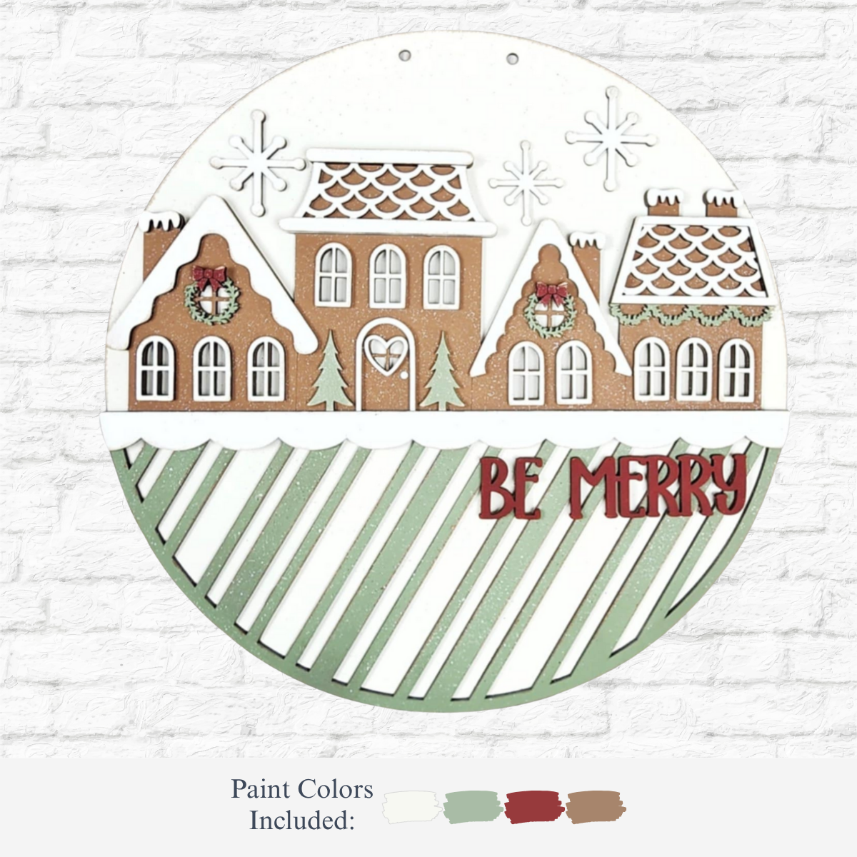 The Rustic Rhode DIY Victorian Gingerbread Door Hanger features gingerbread-style houses with wreaths, snowflakes, and trees on a white and green striped background. Includes four paint colors—perfect for creating unique holiday décor.