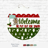 The Rustic Rhode DIY We Put Out For Santa Door Hanger features green and red lettering, festive cookie and milk designs, holly, holiday patterns on a white brick background, plus five paint swatches—ideal for Christmas décor or a unique DIY project.