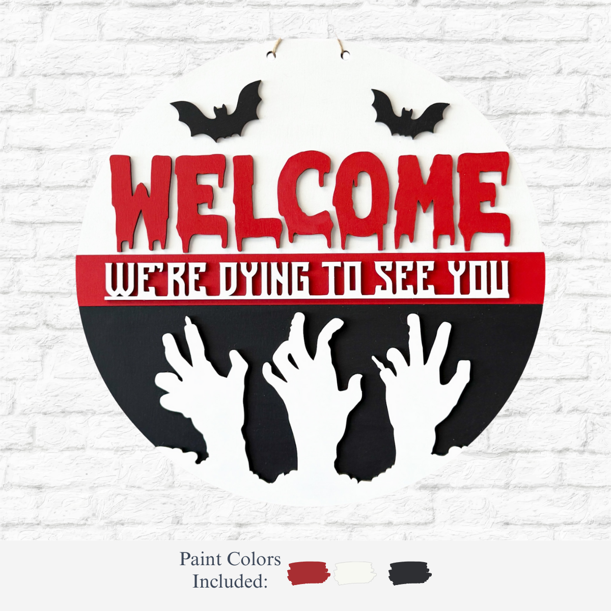 The Rustic Rhode’s DIY We’re Dying To See You Door Hanger features red WELCOME, white WERE DYING TO SEE YOU, black bats and zombie hands, plus red, white, and black paint swatches—perfect for a spooky Halloween door decoration.