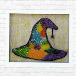 The Rustic Rhode DIY Witchs Hat Sea Glass Frame features a colorful witch hat and black spider in glass on a light wood background, accented with yellow drops—perfect Halloween decor for your home.