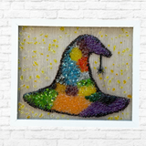The Rustic Rhode DIY Witchs Hat Sea Glass Frame features a colorful witch hat and black spider in glass on a light wood background, accented with yellow drops—perfect Halloween decor for your home.