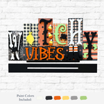 The Rustic Rhodes DIY Witchy Vibes Word Block features playful fonts and patterns—spiders, candy corn, checks—on a Halloween sign displayed on a white brick wall, with paint color options shown below for easy decorating.