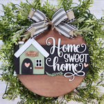 A round wooden sign by The Rustic Rhode for the "Warwick Softball Fundraiser- 10/2/25" features a bow, greenery, a small house with “Home Sweet Home” in white script, a heart, and “Howard” above the door.
