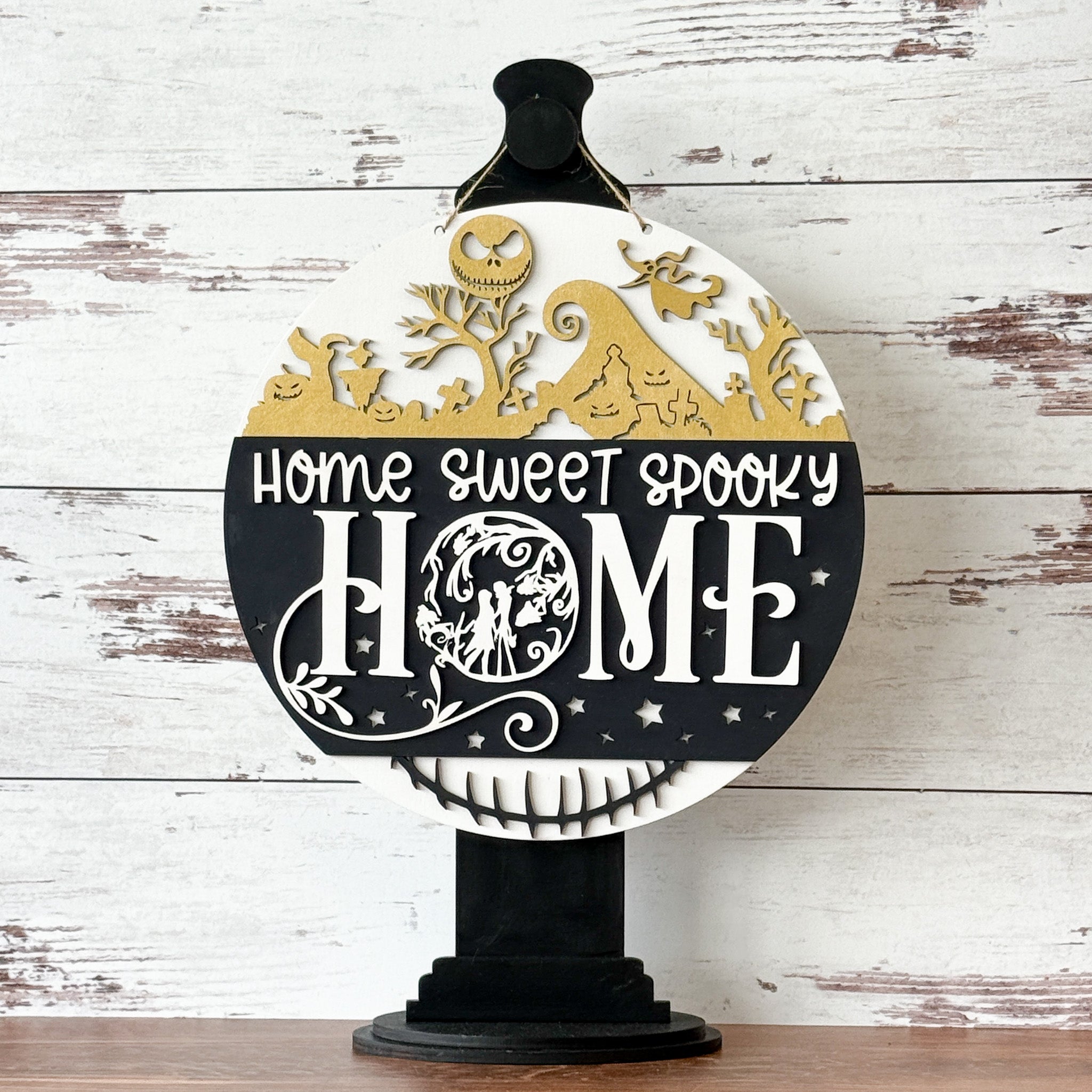 The Rustic Rhode’s “This is Halloween…Craft Night!” sign features gold silhouettes of haunted houses and trees, plus "Home Sweet Spooky Home" in bold white and black. Ideal for Nightmare Before Christmas workshops or Halloween crafts.