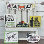 A white wooden chair displays Halloween signs from The Rustic Rhode's Hocus Pocus Craftus Workshop, featuring witch hats, candles, and phrases like Hocus Pocus Co., #Squadgoals, I put a spell on you, and I smell children.