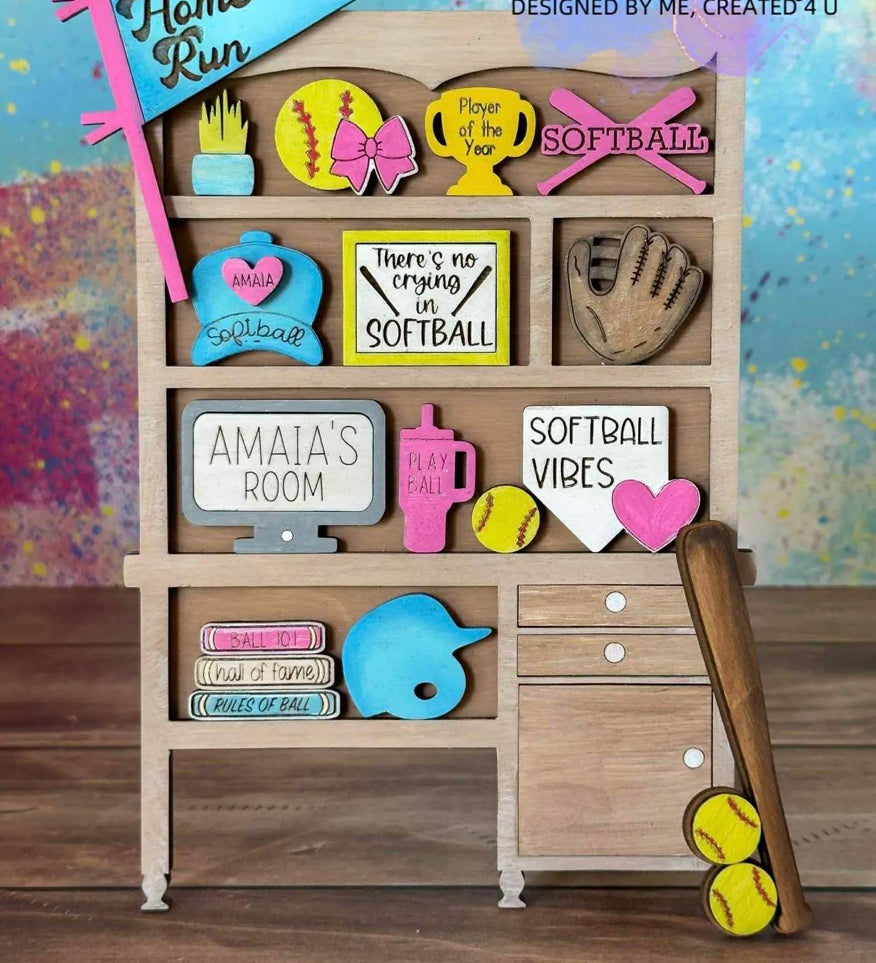 A wooden shelf featuring The Rustic Rhode’s Warwick Softball Fundraiser-10/2/25 door hangers, colorful softball-themed signs, trophies, a glove and bat with softballs, plus phrases like “Home Run” and “There’s no crying in softball.”.